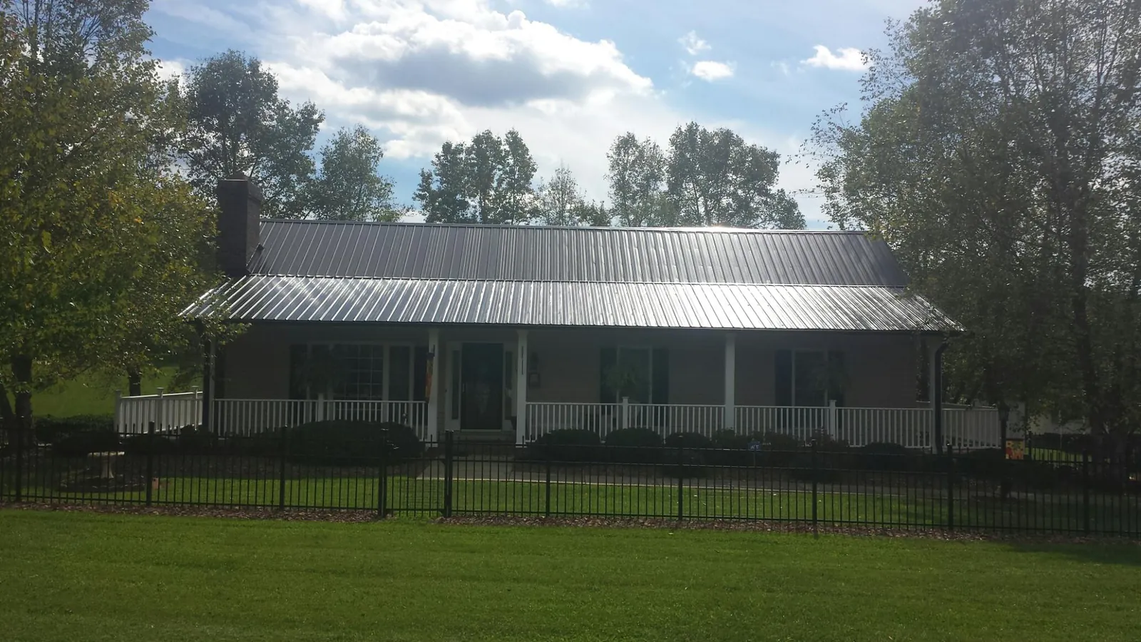 Gray metal roof on a brick ranch with a full width front porch — Gutter Guard Installation work by our crew in Bay City